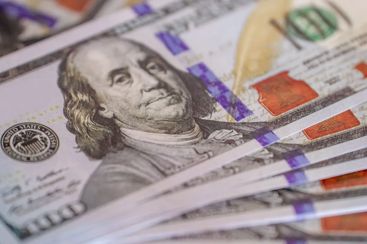 Detailed close-up image of US hundred dollar bills fanned out, showcasing currency detail.